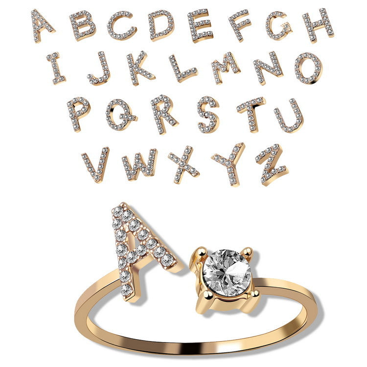 Gold ring with diamond and letter 'A' design on a white background with diamond-studded letters.