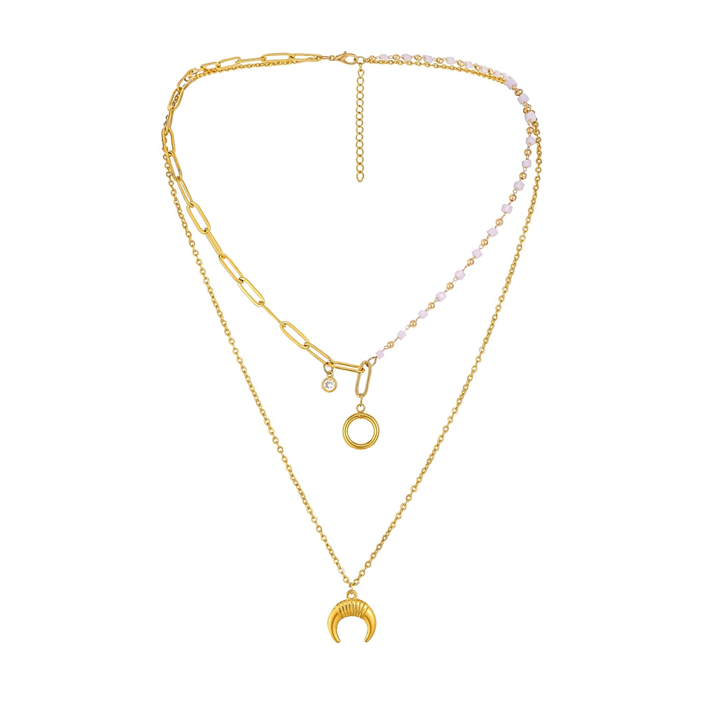 A gold-toned layered necklace set on a plain white background. The necklace features a paperclip chain, a delicate chain with a crescent moon pendant, a small open circle pendant, and a beaded section with pale pink faceted beads.