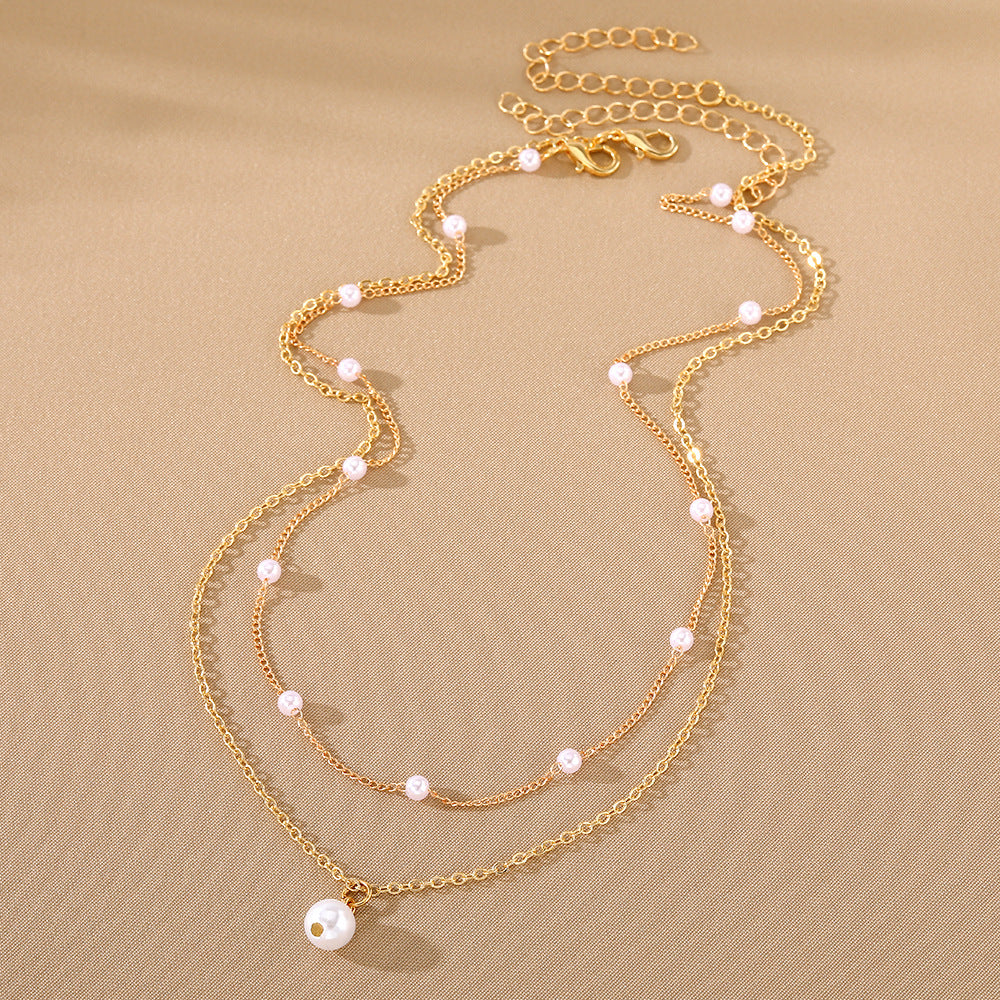 Gold necklace with pearl beads on a beige background