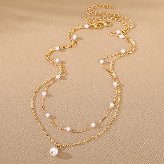 Gold necklace with pearl beads on a beige background