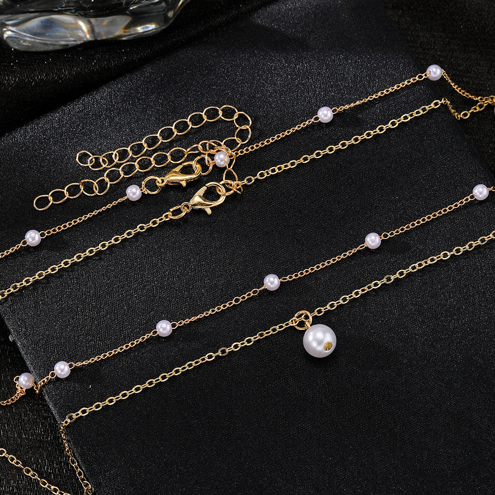 Gold necklaces with pearl pendants on a black surface