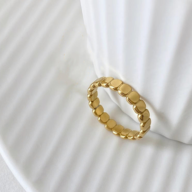 Gold ring with a textured design on a white fabric background